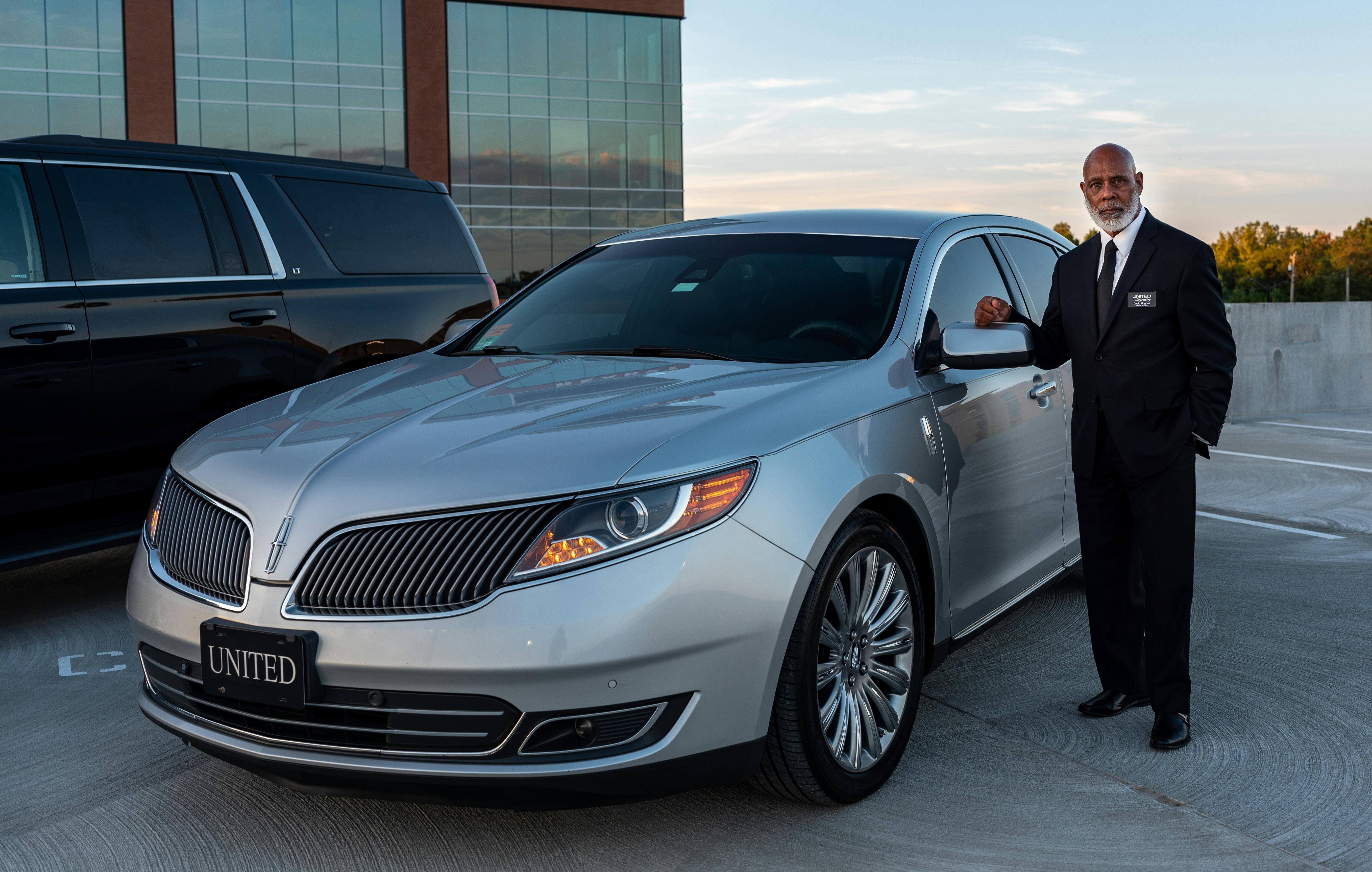 Professional chauffeur standing beside a vehicle to represent the role